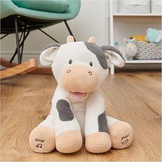 a stuffed cow sitting on top of a wooden floor