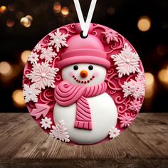 a pink snowman ornament hanging from a wooden table