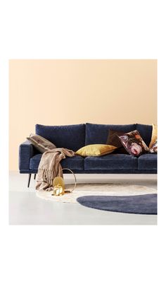 a blue couch sitting on top of a white floor next to a rug and pillows