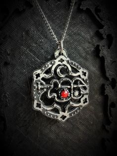 The Clauneck Seal Pendant with Gothic Ornaments is a handcrafted piece made from fine pewter, containing 98% tin, featuring an intricate design that showcases the Seal of Clauneck adorned with elegant gothic embellishments. This pendant measures 3 cm in diameter and is enhanced with a gemstone of your choice, allowing for personalization and individual expression. It comes with a choice of a stainless steel chain in either 18 or 24 inches, ensuring durability and hypoallergenic properties. The S Gothic Silver Necklaces With Antique Finish, Silver Gothic Necklaces With Antique Finish, Silver Gothic Necklace With Antique Finish, Antique Finish Pewter Jewelry As Gift, Handmade Antique Silver Pewter Jewelry, Symbolic Pewter Jewelry As Gift, Symbolic Pewter Jewelry For Gifts, Spiritual Silver Pewter Jewelry, Spiritual Silver Jewelry In Pewter