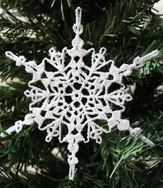 a crocheted snowflake ornament hanging from a christmas tree