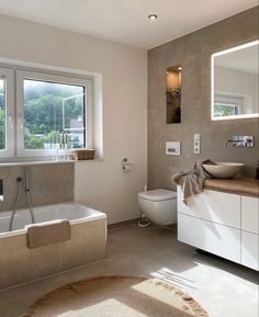 a bathroom with a tub, sink, toilet and window overlooking the outdoors in front of it