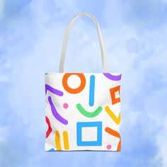 a multicolored tote bag hanging from a string on a blue sky background