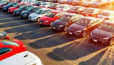 a parking lot filled with lots of different colored cars in it's rows at sunset