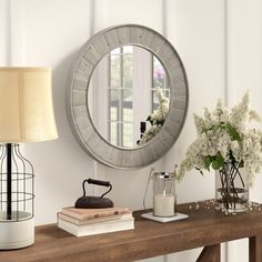 a wooden table topped with a mirror next to a lamp and vase filled with flowers