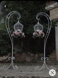 two white birdcages with pink flowers in them are standing next to each other