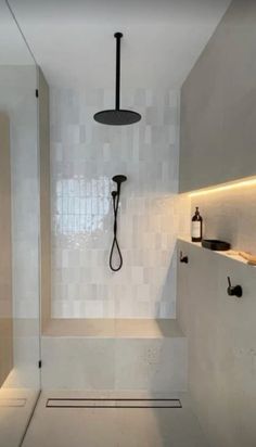 a bathroom with white walls and flooring has a glass shower door that opens up to the bathtub