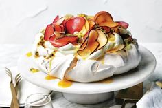 a cake with whipped cream and fruit toppings is on a white plate next to utensils