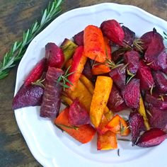 a white plate topped with beets and carrots on top of a wooden table