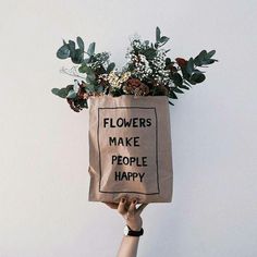 a person holding up a bag with flowers in it that says flowers make people happy