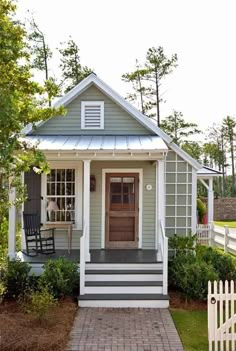 a small gray and white house with steps leading up to the front door that leads into the yard