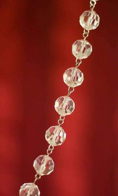 a close up of a necklace with many beads on it's chain, hanging from a red wall