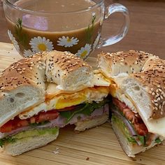 a sandwich cut in half on a cutting board with a cup of coffee behind it