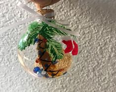 a hand holding an ornament with a palm tree on it