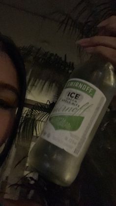 a woman holding up a bottle of ice water