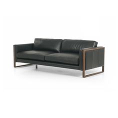 a black leather couch sitting on top of a white floor next to a wooden frame