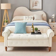 a white bed sitting next to a table with a bottle of wine on top of it