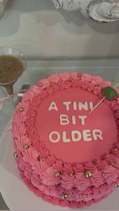 a pink cake that says, a tint bit older on it with gold decorations