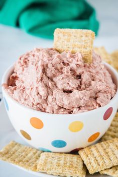 a white bowl filled with pink dip surrounded by crackers