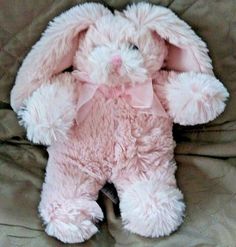 a pink stuffed rabbit sitting on top of a bed