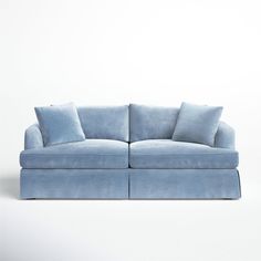 a blue couch with two pillows on the back and one arm folded over it's sides