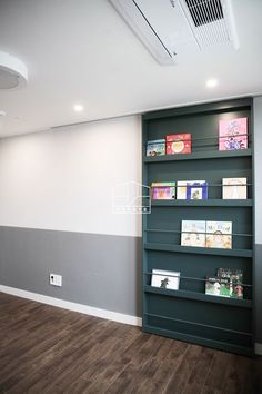 an empty room with bookshelves on the wall and hard wood flooring in front of it