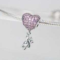 This is charm only, bracelet is sold separately. Bring some extra joy and sparkle to your Valentine's Day with this exquisite heart and teddy bear combo charm. Perfect for adding to a bracelet or necklace, this solid 925 sterling silver charm features a dazzling pink cubic zirconia pave heart and a tiny teddy bear for a touch of cuteness. Show your love with this adorable charm, plated with shiny platinum to keep it shining for years to come. Materials: 925 sterling silver, cubic zirconiaFinish: Sterling Silver Heart Charms With Dangling Details, Pink Heart-shaped Dangling Charms, Pink Heart-shaped Sterling Silver Charm Bracelet, Pink Heart Charm Bracelet In Sterling Silver, Pink Sterling Silver Charm Bracelet With Heart, Sterling Silver Pink Heart Charm Bracelet, Pink Sterling Silver Dangle Charms, Cute Silver Dangle Charms, Pink Sterling Silver Charm Bracelet With Dangling Charms