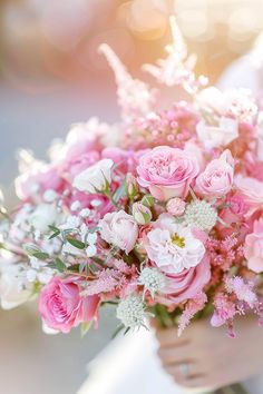 a woman holding a bouquet of pink and white flowers