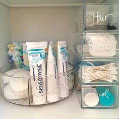 the bathroom is organized with clear containers and toothpaste, soaps, and lotion