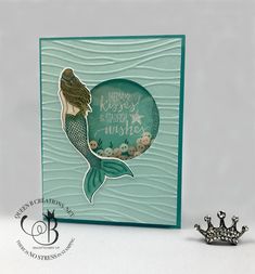 a card with a mermaid on it next to a crown