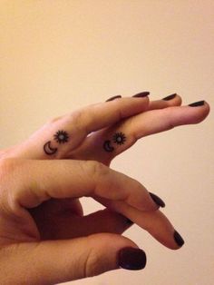 two fingers with sun and moon tattoos on them, one is pointing at the other