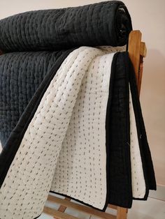 a black and white quilted blanket on a wooden rocking chair with it's back facing the camera