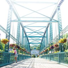 a woman walking across a bridge with lots of flowers