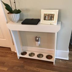 a white dog bowl stand with three bowls on it and a photo frame next to it