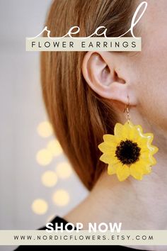 a woman wearing yellow and black earrings with a sunflower on it