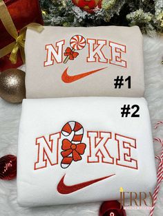 two white bags with red and orange designs on them sitting next to a christmas tree