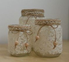 three mason jars with lace and wood beads on the lids are sitting on a table