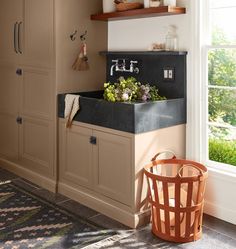 a kitchen sink sitting under a window next to a trash can and wooden shelfs