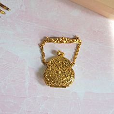 "Vintage 1955 -1959 Lisner Handbag Purse Locket Brooch, Kiss Clasp, Gold Tone, Ornate Raised Design, Chain & Bar, Costume Jewelry, Women This unique locket-style brooch from Lisner Jewelry, was made between 1955 and 1959, based on the mark, which was only used between those year.  It's in very good condition, and all pieces function as they were intended, too.  Please see all photos, as they are considered part of the description.  Purse Width 1 3/4\"  Total Length 2.5\"" Antique Gold Brooches From Vintage Collection, Antique Gold Brooches For Vintage Collection, Gold Antique Brooches For Vintage Collection, Gold Brooches With Vintage Charm For Gift, Gold Brooches With Vintage Charm As Gift, Vintage Metal Brooches For Gift, Vintage Gold-tone Brooches For Formal Occasions, Gold Costume Jewelry Brooches For Vintage Events, Heirloom Gold Brooches For Evening