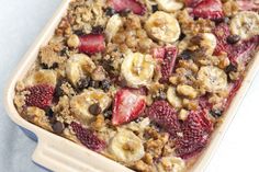 a casserole dish with strawberries, bananas and granola in it on a table