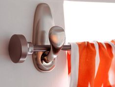 an orange and white striped curtain is hanging on the wall next to a metal hook