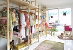 a clothing store with lots of clothes hanging on the racks and rugs in front of it