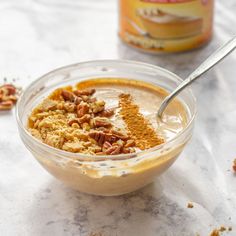 a glass bowl filled with food next to a can of nut butter on a table