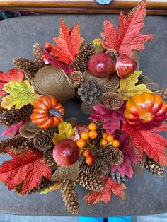 a wreath made out of pine cones and autumn leaves