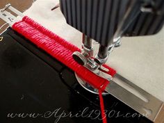 the sewing machine is being worked on with red thread and scissors to make it easier for someone to sew