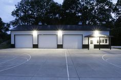 an empty basketball court at night with lights shining on the building and trees in the background