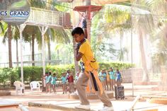 a young boy in yellow shirt and tan pants doing tricks on a skateboard while others watch