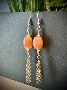 Embrace the bohemian spirit with these elegant, handcrafted earrings featuring stunning barrel-shaped Cherry Blossom Agate beads, meticulously wire-wrapped in sterling silver. The earrings are accented with a playful tassel of both sterling silver and 14k gold-filled chains, adding a touch of mixed-metal charm. The combination of metals and the soft hues of the Cherry Blossom Agate give these earrings a unique, earthy vibe, perfect for boho-chic styles. Finished with sterling silver ear wires, t Carnelian Dangle Earrings With Natural Stones, Carnelian Gemstone Dangle Earrings, Carnelian Drop Earrings With Natural Stones, Carnelian Natural Stones Dangle Earrings, Carnelian Natural Stone Drop Earrings, Bohemian Wire Wrapped Earrings As Gift, Nickel-free Agate Earrings For Gifts, Elegant Handmade Agate Earrings, Bohemian Amber Drop Earrings