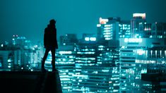 a person standing on top of a roof in front of a cityscape at night