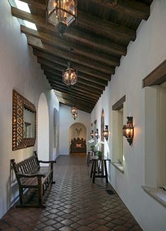 the hallway is lined with wooden benches and hanging lanterns on the ceiling, along with decorative wall sconces